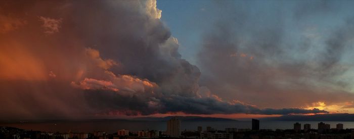 Panoramic view of city against dramatic sky during sunset