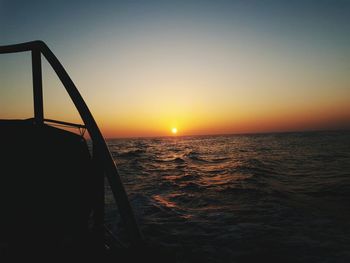 Boat sailing in sea against clear sky during sunset