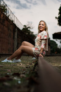 Portrait of smiling woman sitting on railroad track