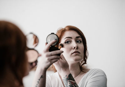 Young woman applying make-up at home