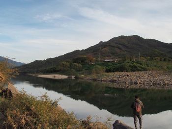 Man standing by lake against sky