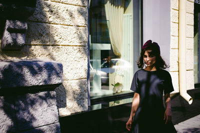 Beautiful young woman in black dress standing by building