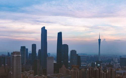 Modern buildings in city against sky during sunset