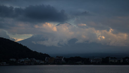 Sea by cityscape against sky during sunset