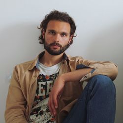 Portrait of young man sitting against wall