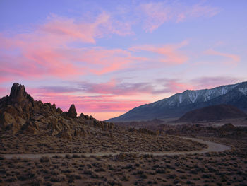 Cotton candy clouds, a dirt road winds through rock formations.