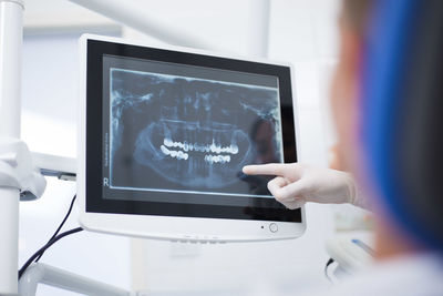 Cropped hand of doctor pointing at display screen in hospital