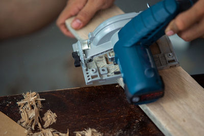 Close-up of a carpenter using a circular saw to cut a plank of wood
