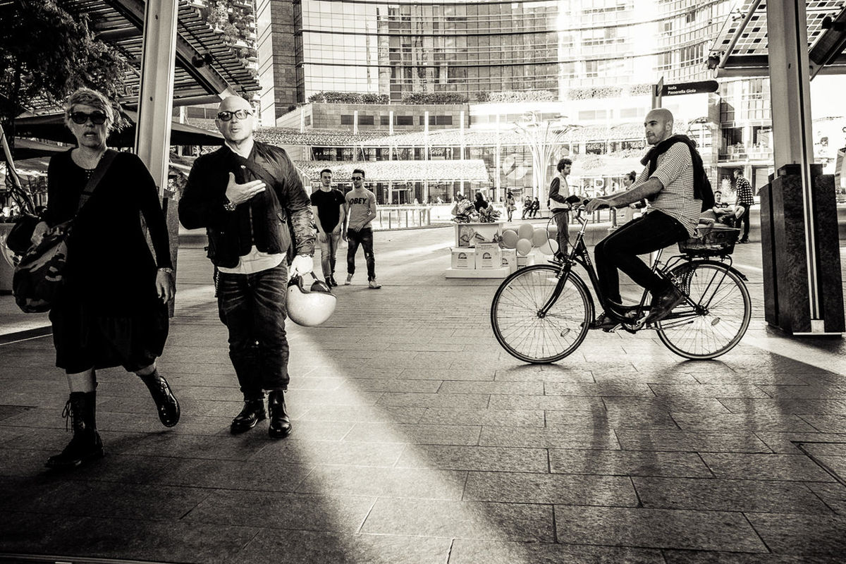 city, bicycle, building exterior, architecture, transportation, real people, street, men, group of people, built structure, city life, land vehicle, women, lifestyles, mode of transportation, people, motion, full length, walking, adult, outdoors, riding