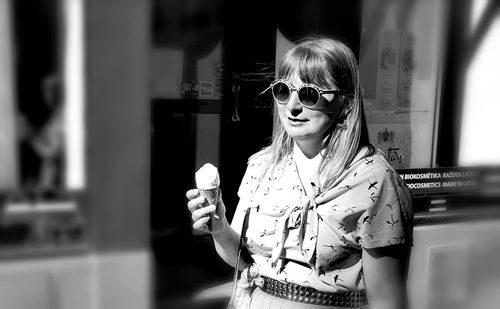 Portrait of young woman wearing sunglasses standing outdoors