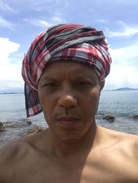 Portrait of mature man on beach against sky