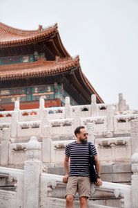 Full length of young man outside building against clear sky