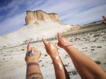 Cropped hands pointing at rock formation on landscape