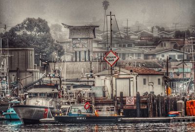 Boats moored at harbor against sky in city