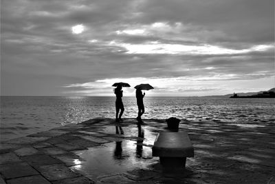 People standing on beach against sky