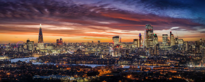 Illuminated cityscape against sky during sunset