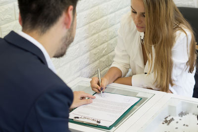 Businesswoman signing contract with male colleague in office