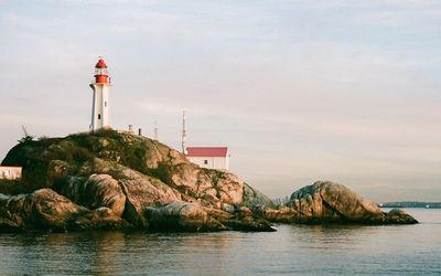 Lighthouse by sea against sky