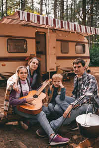 Happy family on camping trip relaxing in the autumn forest camper trailer. fall season outdoors trip