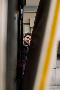 Portrait of young man looking through window