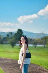 Young woman standing on road against sky