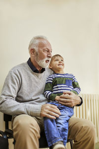 Boy sitting on grandfather's lap in waiting room