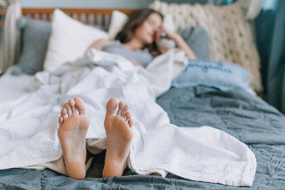 Midsection of woman sleeping on bed at home