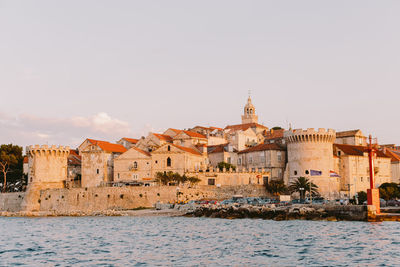 Buildings by sea against sky