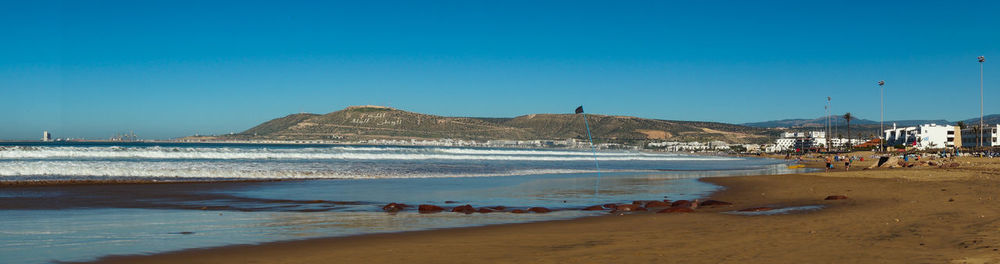 Scenic view of beach against clear blue sky