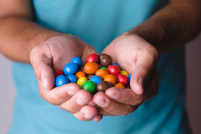 Adult male holding candies with both hands.