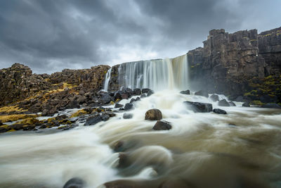 View of waterfall against cloudy sky