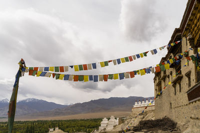 Low angle view of flags hanging on mountain against sky