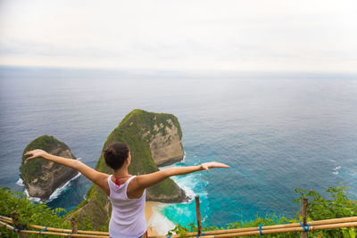 Rear view of woman standing in sea against sky