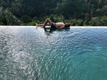 Man relaxing in swimming pool against trees