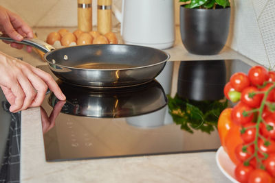Woman turn on induction hob with frying pan