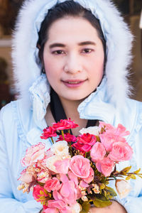 Portrait of smiling woman holding pink flower