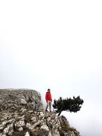 Man standing on cliff against sky during foggy weather