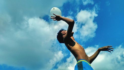 Low angle view of man with arms raised against sky