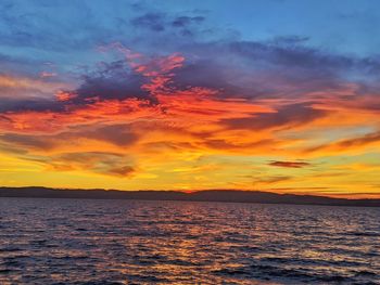 Scenic view of sea against dramatic sky during sunset