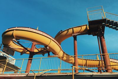 Low angle view of amusement park ride against clear blue sky