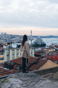 Rear view of man standing by cityscape against sky