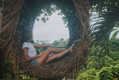 Woman sitting on tree trunk