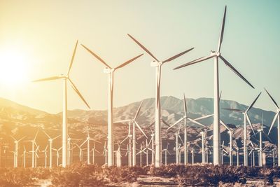 Wind turbines against sky during sunset