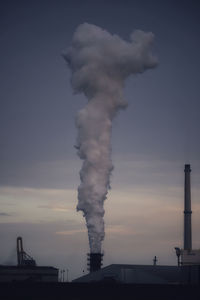 Smoke emitting from chimney against sky