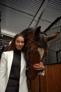 Portrait of young woman standing in stable