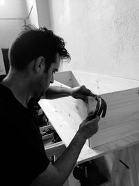 Young man hammering furniture at home