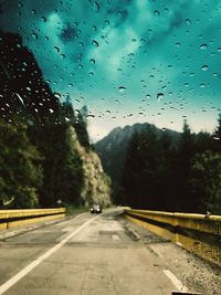 Road seen through wet glass window