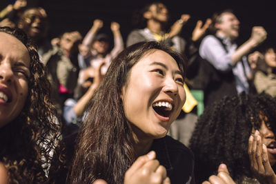 Excited young woman shouting during game in stadium on sunny day
