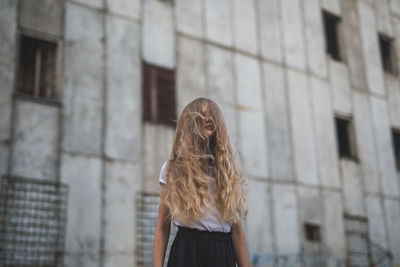 Rear view of woman standing against building