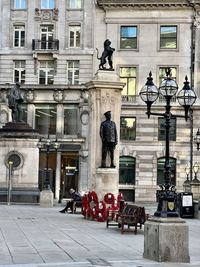 Statue on street against building in city